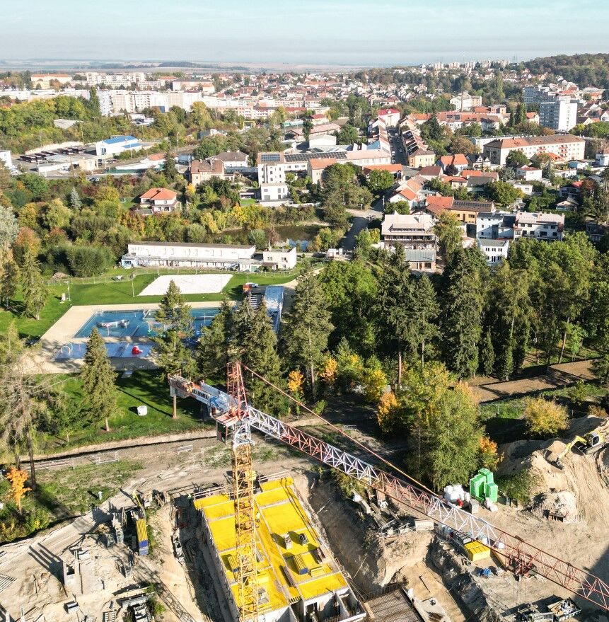 Stavba druhé etapy z dronu, za ní koupaliště a Slaný